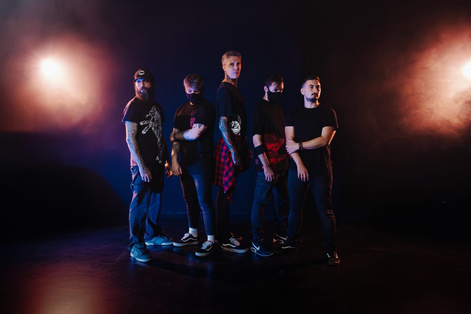 Astraline, the five members on a dark stage between two stage lights